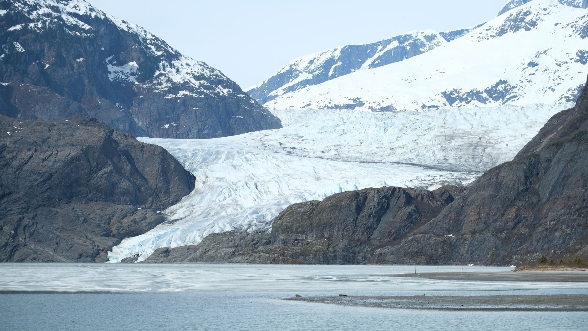 Weitwinkelblick auf den Mendenhall-Gletscher, der zwischen rauen, schneebedeckten Bergen zum See in Juneau, Alaska, fließt.